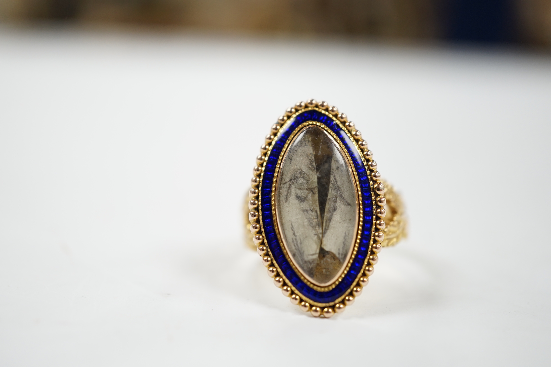 A 19th century 15ct and blue enamel set navette shaped mourning ring, with damaged inset ivory panel, size O, gross weight 5.5 grams. Submission reference Q8ZGC6ZR